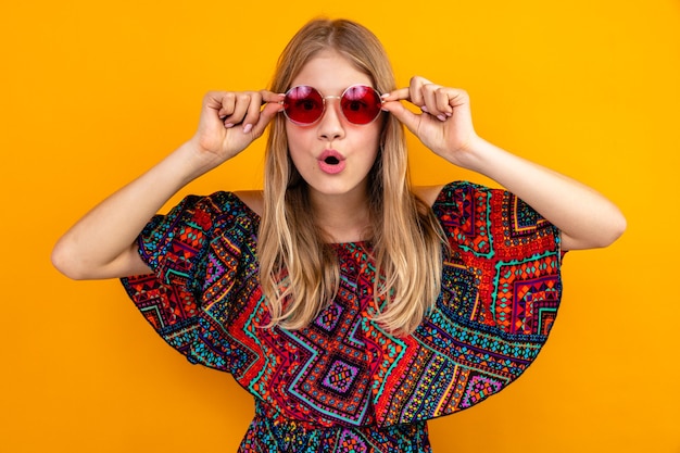 Chica eslava rubia joven sorprendida con gafas de sol mirando al frente