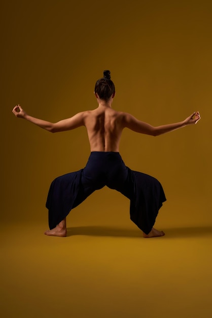 Chica con la espalda desnuda practicando pose de yoga