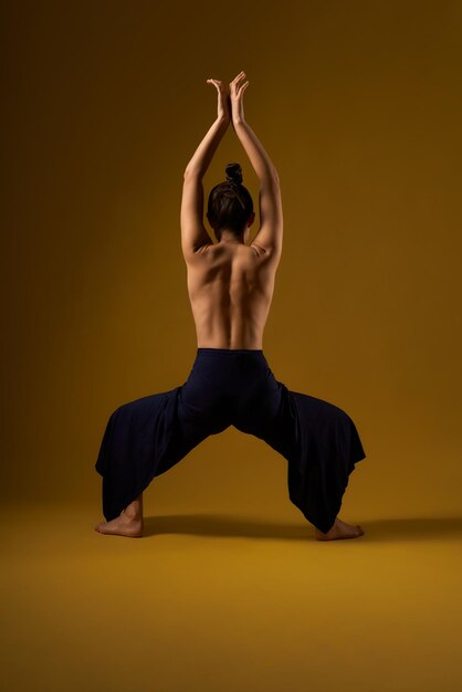 Chica con la espalda desnuda practicando yoga en el estudio