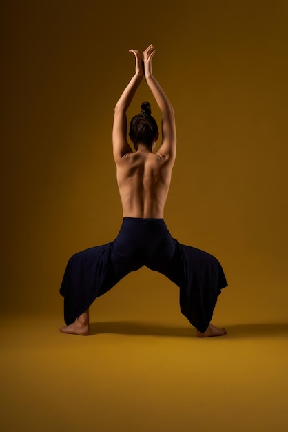 Chica con la espalda desnuda practicando yoga en el estudio