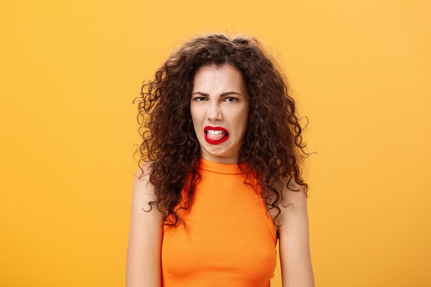 Chica está disgustada con comida en fila sacando la lengua y frunciendo el ceño mostrando aversión y disgusto tal ...