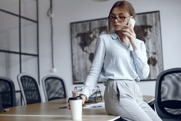 Chica está sentada en la mesa. Mujer hablando por teléfono. Morena tomando café