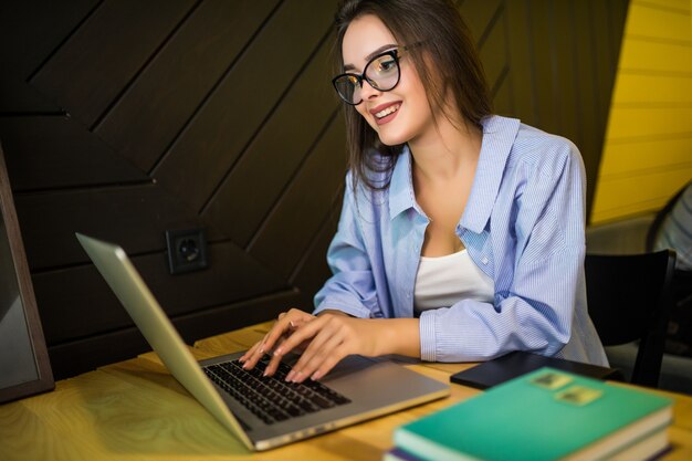 Chica está trabajando en la computadora portátil en el cibercafé