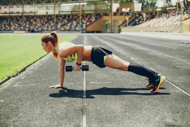 La chica en el estadio está jugando deportes.