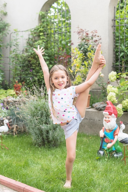 Chica estirando su pierna de pie en el jardín