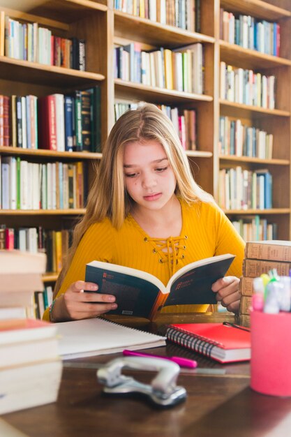 Chica estudiando en la biblioteca de la escuela