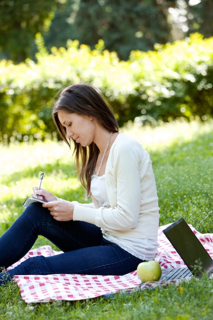 Chica estudiando en el parque verde