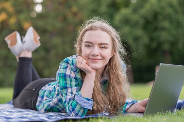 Chica estudiando con portátil en mantel de picnic