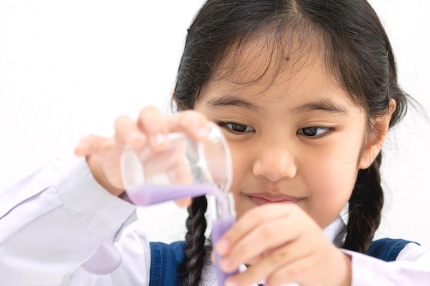 Chica estudiante asiática feliz haciendo experimentos científicos en los laboratorios escolares