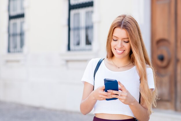 Chica estudiante feliz chateando a través de la aplicación móvil