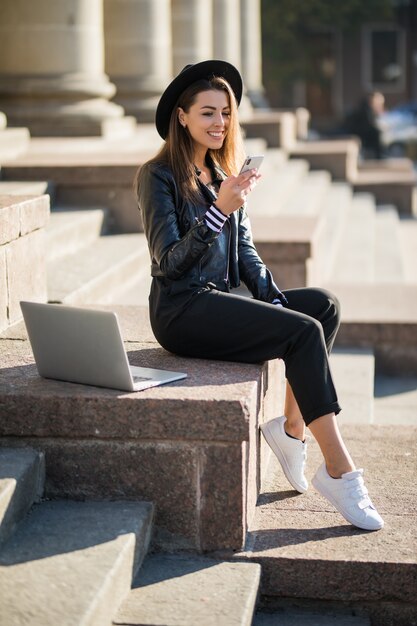 Chica estudiante joven empresaria trabaja con su computadora portátil de marca en el centro de la ciudad