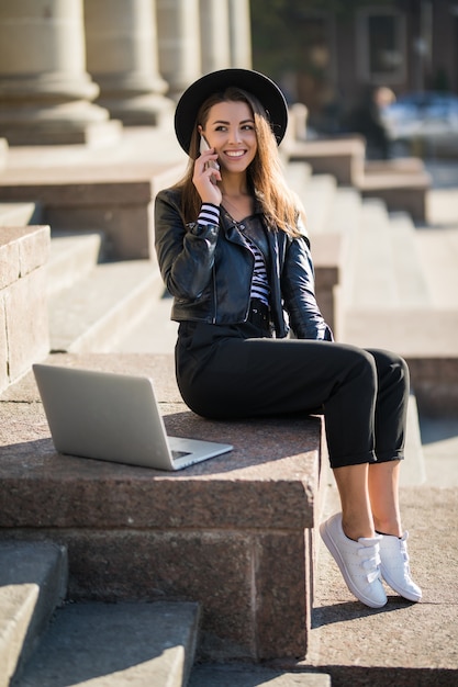 Chica estudiante joven empresaria trabaja con su computadora portátil de marca en el centro de la ciudad