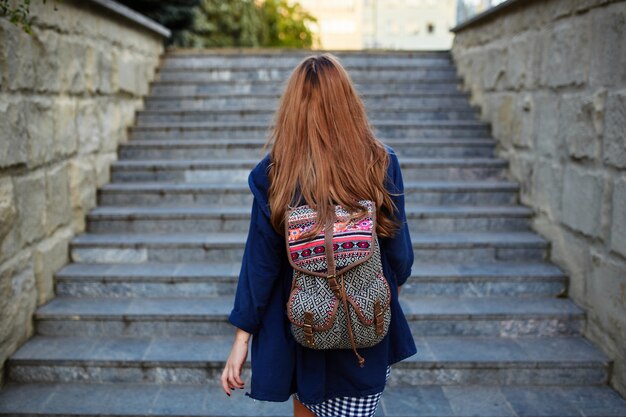 Chica estudiante con una mochila subiendo escaleras