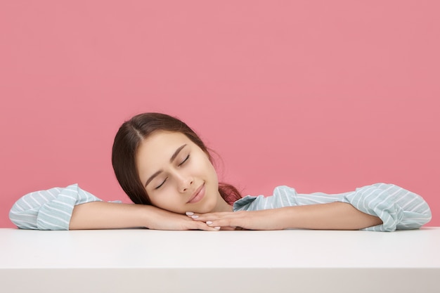 Chica estudiante soñolienta con camisa azul a rayas durmiendo pacíficamente durante la clase en la universidad, acolchándose la cara con las manos, manteniendo los ojos cerrados. Personas, estilo de vida, sueño, cansancio, aprendizaje y educación.