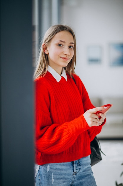 Chica estudiante en suéter rojo con teléfono