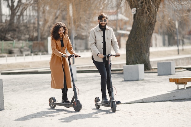 Chica europea anindian guy andar en scooter y sonreír.