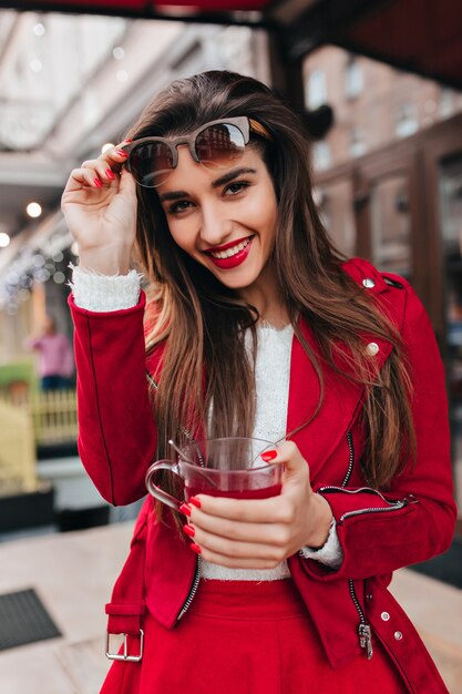 Chica europea inspirada con maquillaje brillante riendo en el espacio urbano