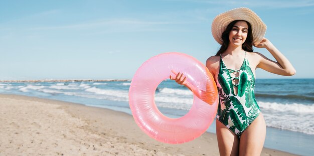 Chica feliz con anillo inflable en la playa