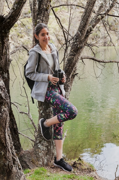 Chica feliz apoyada en un árbol al aire libre