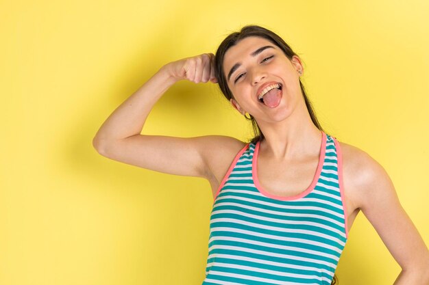 Chica feliz apretando su bíceps y sacando su lengua Foto de alta calidad