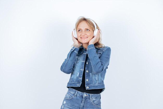 Chica feliz con auriculares está mirando hacia arriba sosteniendo auriculares sobre fondo blanco.