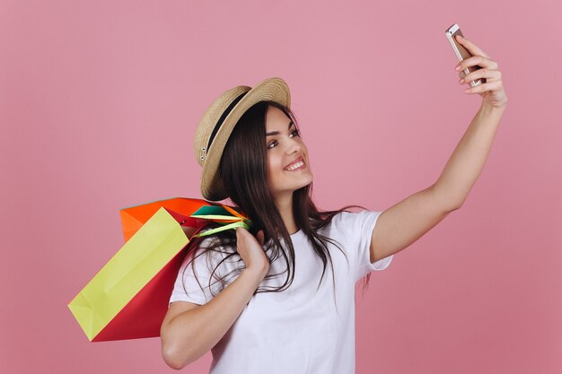 Chica feliz con coloridos bolsos de compras toma selfie en su teléfono