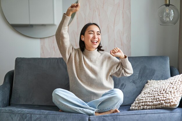 Chica feliz y despreocupada cantando y escuchando música en la aplicación de teléfono inteligente usando el teléfono móvil como micro