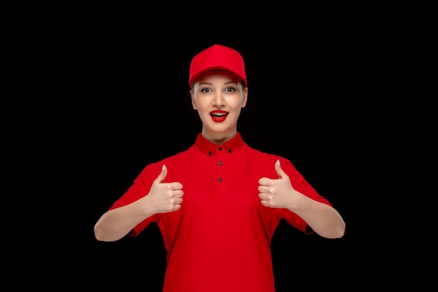 Chica feliz del día de la camisa roja mostrando un buen gesto en una gorra roja con camisa con lápiz labial