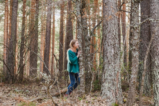 Chica feliz escondida junto a un árbol