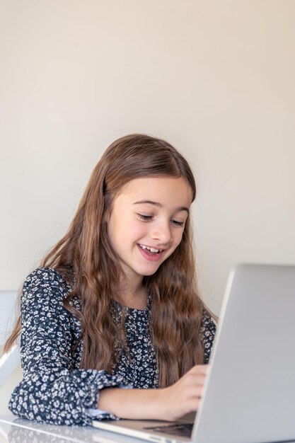Una chica feliz está trabajando en una computadora portátil.