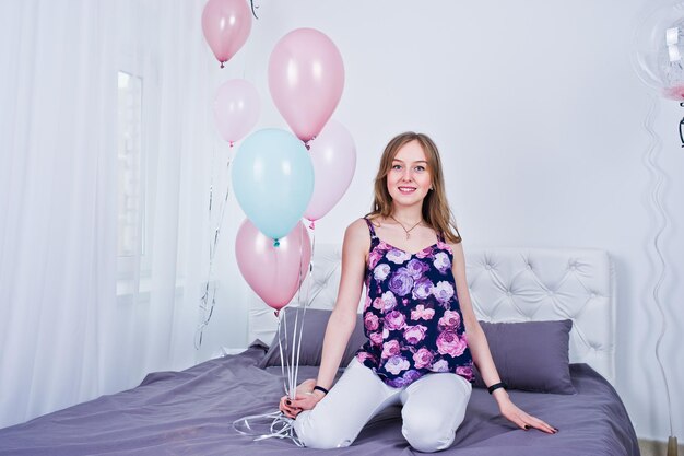 Chica feliz con globos de colores en la cama en la habitación Celebrando el tema del cumpleaños