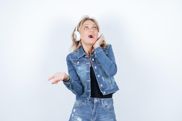 Chica feliz sorprendida con auriculares está mirando hacia arriba sobre fondo blanco.