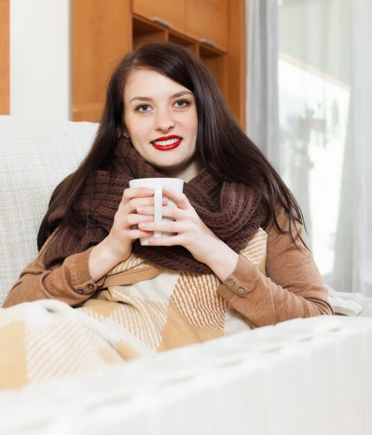 Foto gratuita chica feliz con taza cerca de calorifer