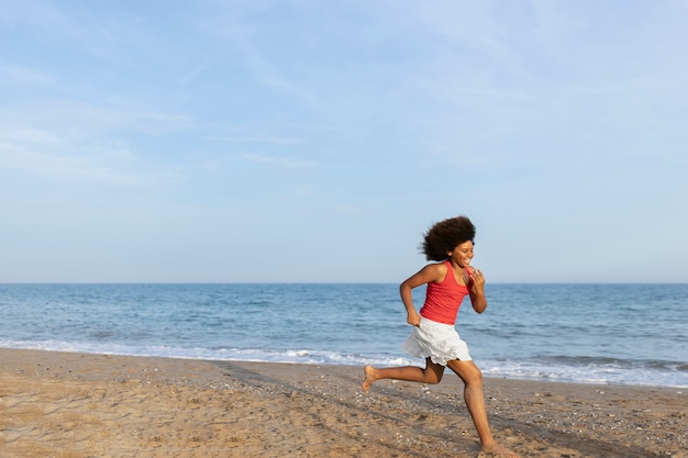 Foto gratuita chica feliz de tiro completo corriendo en la playa