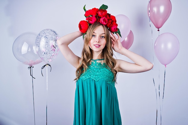 Chica feliz en vestido verde turquesa y corona con globos de colores aislados en blanco Celebrando el tema del cumpleaños
