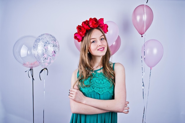 Chica feliz en vestido verde turquesa y corona con globos de colores aislados en blanco Celebrando el tema del cumpleaños