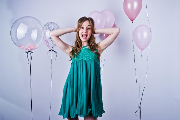 Chica feliz en vestido verde turquesa con globos de colores aislados en blanco celebrando el tema del cumpleaños