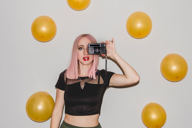 Chica de fiesta con globos y cámara