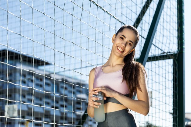 Chica fitness sonriendo tiene botella de agua