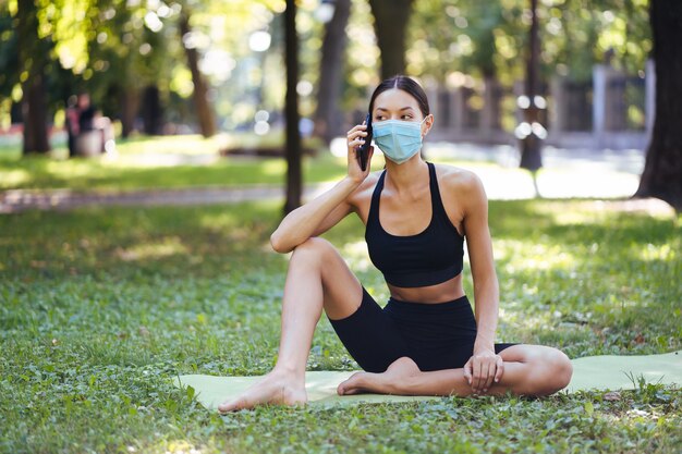 Chica fitness con un teléfono inteligente en la naturaleza, disfruta del entrenamiento deportivo