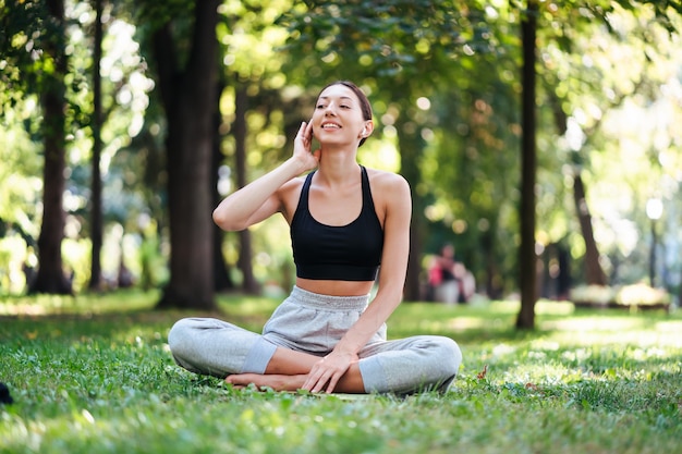 Chica fitness con un teléfono inteligente en la naturaleza, disfruta del entrenamiento deportivo