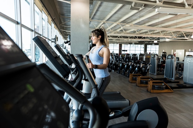 Chica fitness usando bicicleta elíptica