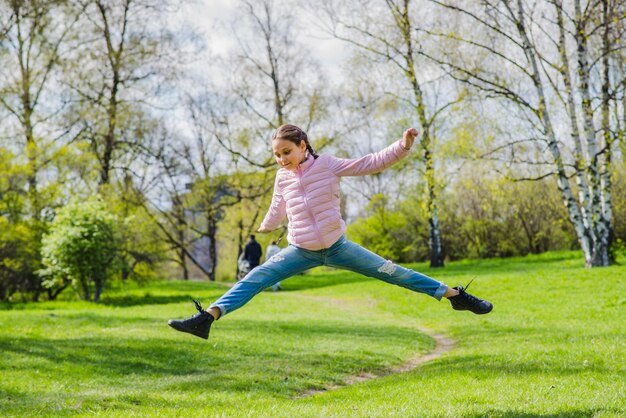 Chica flexible saltando al aire libre