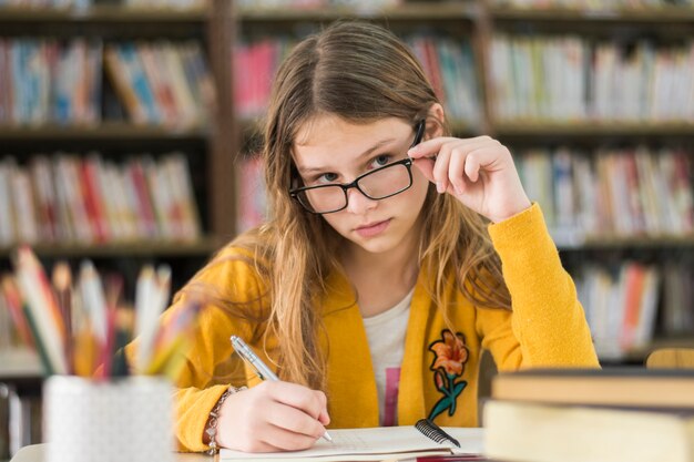 Chica con gafas estudiando en la biblioteca