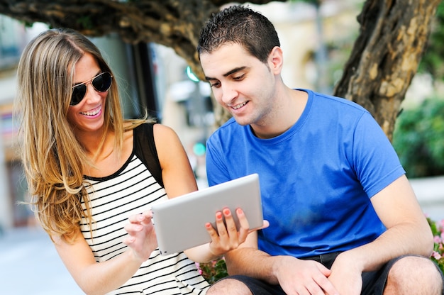 Foto gratuita chica con gafas mostrando algo en la tableta a su amigo