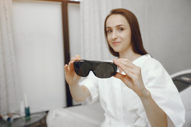 Chica con gafas de seguridad sentado en un estudio de cosmetología