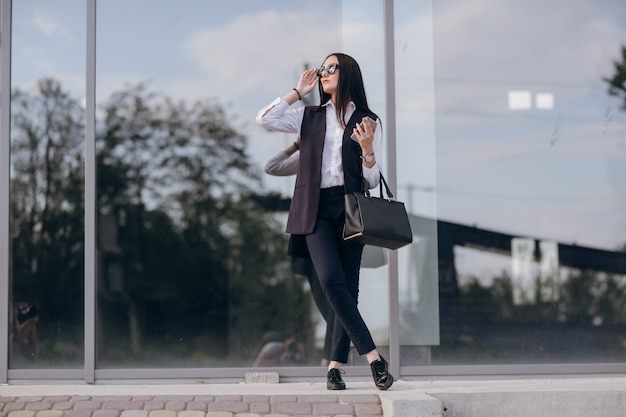 Chica con gafas de sol apoyada en un cristal oscuro