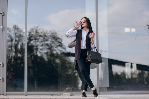 Chica con gafas de sol apoyada en un cristal oscuro