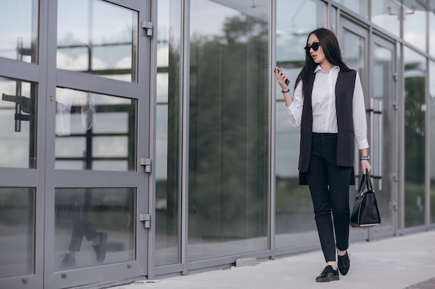 Foto gratuita chica con gafas de sol mirando su teléfono inteligente