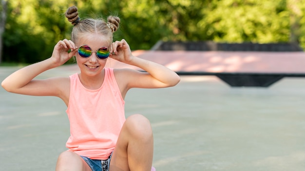 Foto gratuita chica con gafas de sol sentado en el parque